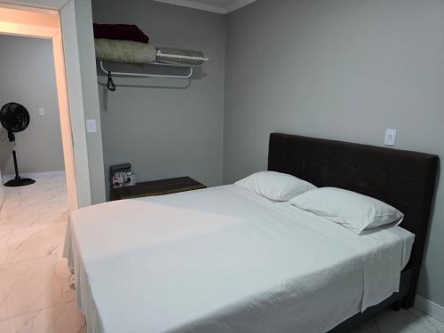 a bed with white sheets and pillows in a room at Apartamento 8min da praia e 11 do Beto Carrero in Penha