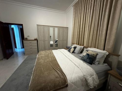 a bedroom with a large bed and a dresser at Stylish 2 Bedroom with 2 outside area in Abu Dhabi