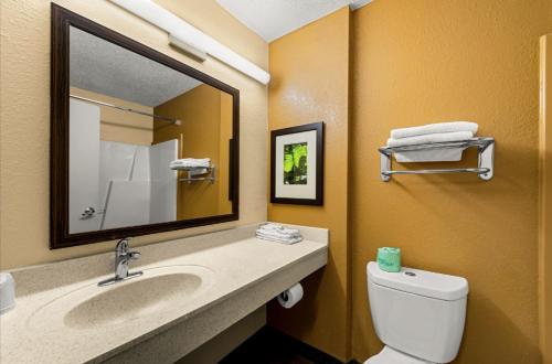 a bathroom with a sink and a toilet and a mirror at Suburban Studios Winston-Salem near Hanes Mall in Winston-Salem