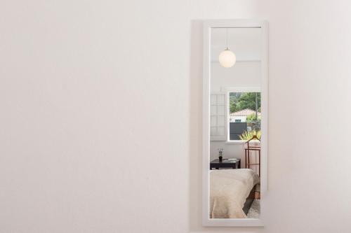 um quarto branco com uma cama e um espelho em Casa das Camélias - Family Villa by the lagoon em Sete Cidades