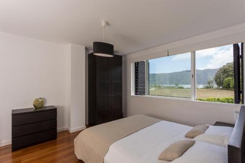 a bedroom with a bed and a large window at Casa das Camélias - Family Villa by the lagoon in Sete Cidades