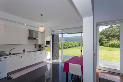 a kitchen with a table and a large window at Casa das Camélias - Family Villa by the lagoon in Sete Cidades