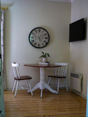 a table with two chairs and a clock on the wall at Birdsland Suite in Belgrave Heights
