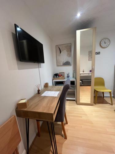 a living room with a table and a television on a wall at The Bungalow by SJP - Double Room in Northamtonshire