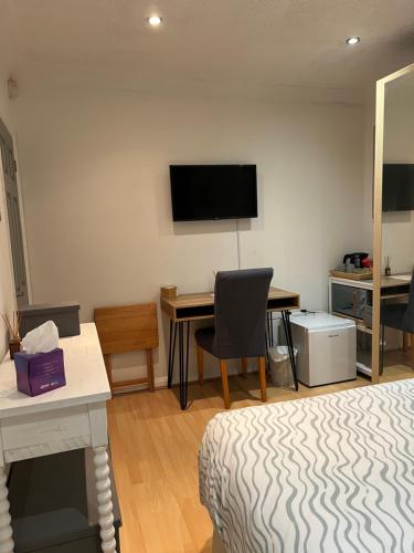 a room with a bed and a desk and a television at The Bungalow by SJP - Double Room in Northamtonshire