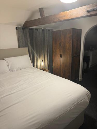 a bedroom with a white bed and a wooden cabinet at The Rampant Horse Public House in Fakenham