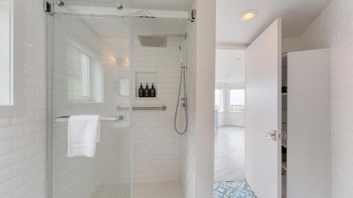 a white bathroom with a shower with a glass door at Sanctuary by the Sea by AvantStay Waterfront Views in Arch Cape