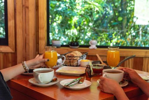 two people sitting at a table with coffee and orange juice at Lican Lodge in Villarrica