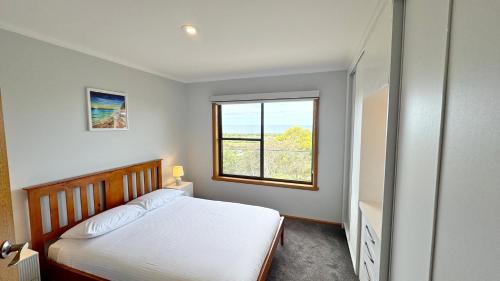 a bedroom with a bed and a large window at Ocean Views on Lyrebird in Lakes Entrance