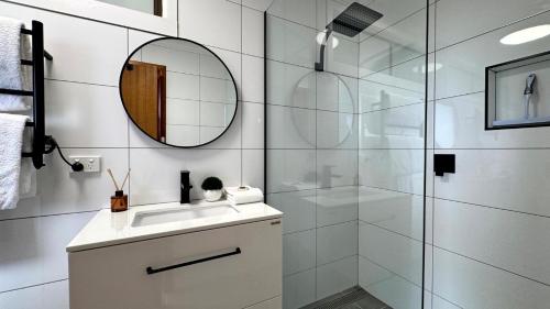 a bathroom with a shower and a sink and a mirror at Ocean Views on Lyrebird in Lakes Entrance