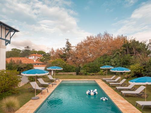 a swimming pool with chairs and umbrellas at Maison Resaurie - Hôtel in Biarritz