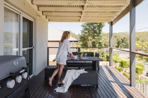 a woman standing on a deck with a grill at Ocean Stays - Mollymook in Mollymook