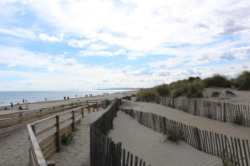 a beach with a wooden fence and people on the beach at Mercure Port La Grande Motte in La Grande-Motte