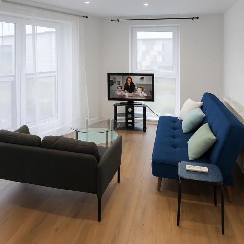 a living room with a blue couch and a tv at Morris lodge in Kew