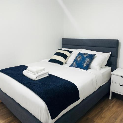 a large bed with blue and white sheets and pillows at Morris lodge in Kew