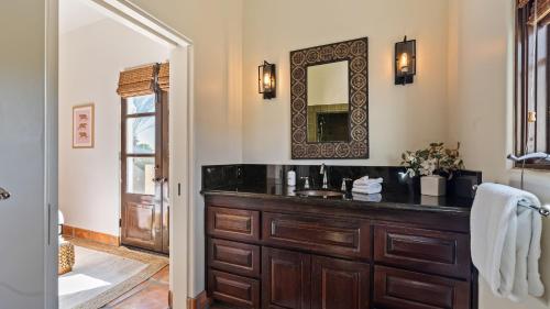a bathroom with a wooden vanity and a mirror at Luxe 7BDR Oasis w Pool Putting Green Game Room Villa Del Gallo by AvantStay in Bermuda Dunes