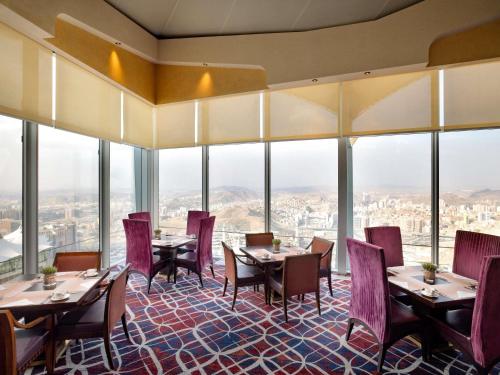 Un restaurante con mesas y sillas y grandes ventanales. en Makkah Clock Royal Tower, A Fairmont Hotel, en La Meca