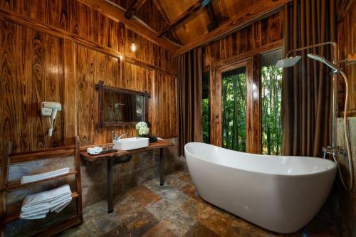 a bath tub in a bathroom with wooden walls at Asia Tropical Resort and Spa in Làng Coc