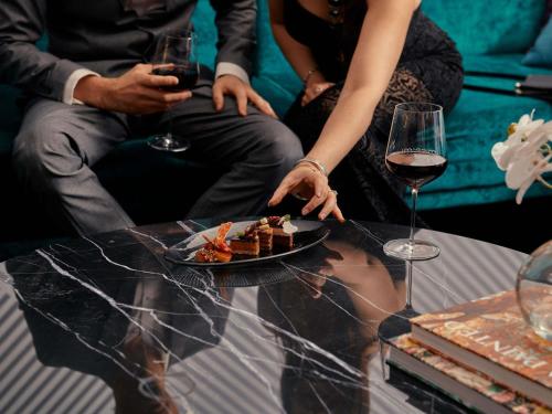 Movenpick Hotel Melbourne On Spencer في ملبورن: مجموعة من الناس يجلسون حول طاولة مع طبق من الطعام