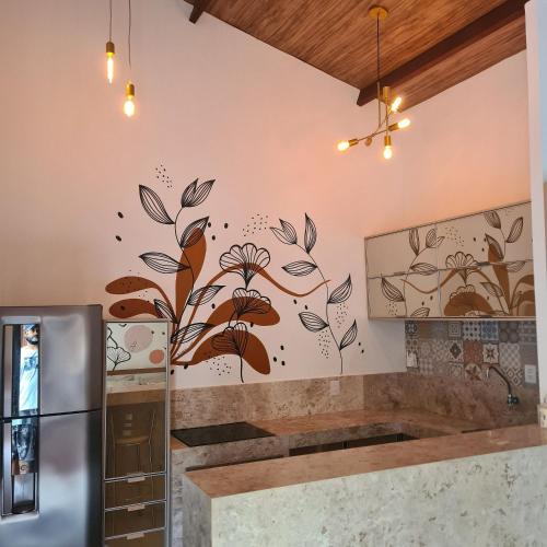 a kitchen with a wall mural of flowers and leaves at Solar Águas Pipa Stays in Pipa