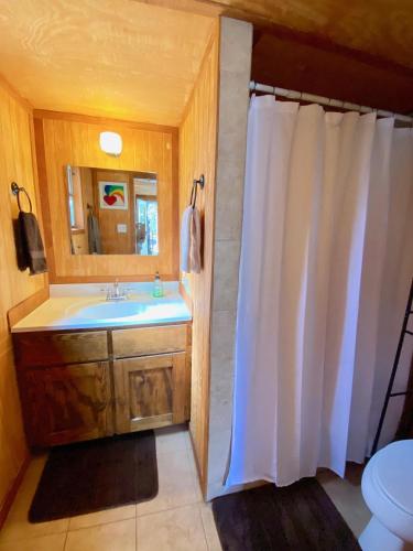 a bathroom with a white shower curtain and a sink at On the Rocks! in Concan