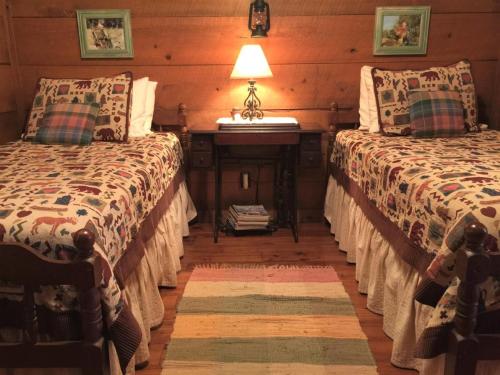 a bedroom with two beds and a table with a lamp at La Casita in Concan