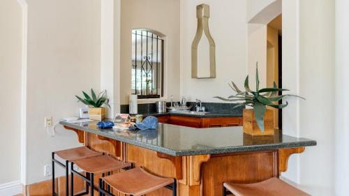 a kitchen with a counter with a sink and stools at Grapevine by AvantStay Secluded 5BR Villa 4 Acres of Vineyards Avo Groves in Temecula