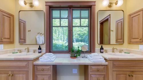 a bathroom with two sinks and two mirrors at Goldilocks by AvantStay Luxury Waterfront Home in Greenbank