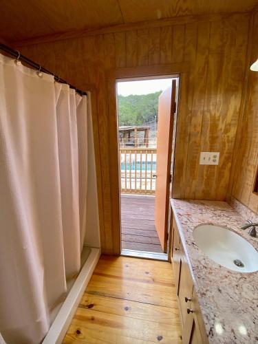 a bathroom with a sink and a door to a deck at HILLSIDE in Concan