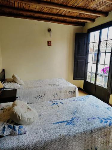 two beds in a room with two windows at Solue in Duitama