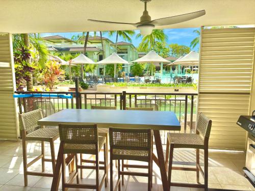 Lagoon Swimout Absolute Pool Front - Tropical Paradise -in Sea Temple Pt Douglas في ميناء دوغلاس: طاولة زرقاء وكراسي على فناء مع مظلة