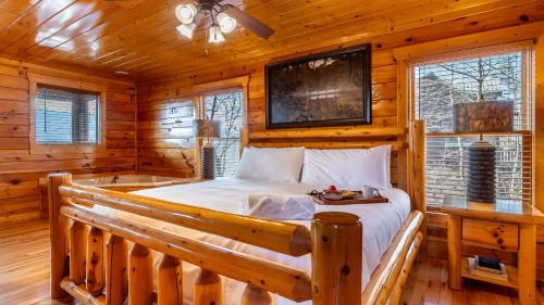 ein Schlafzimmer mit einem Bett in einer Blockhütte in der Unterkunft Misty Mountain by AvantStay Hot Tub Mountain Views Theater Pool Table in Gatlinburg