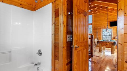 ein Badezimmer mit einer Badewanne und einer Holzwand in der Unterkunft Misty Mountain by AvantStay Hot Tub Mountain Views Theater Pool Table in Gatlinburg