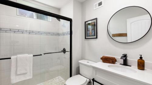 a bathroom with a shower and a toilet and a mirror at Hot Tub Fire Pit Deck Views Near the Lake The Matterhorn Manor by AvantStay in Crestline