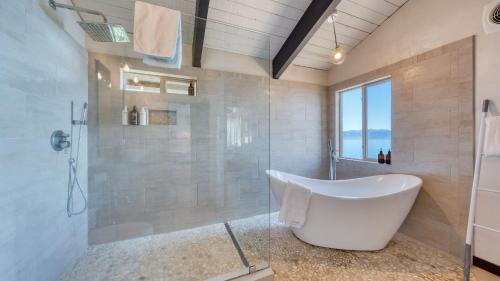 a bathroom with a tub and a shower with a window at Lakeview by AvantStay Private Waterfront Cabin on Lake Tahoe w Hot Tub Views in Tahoe Vista