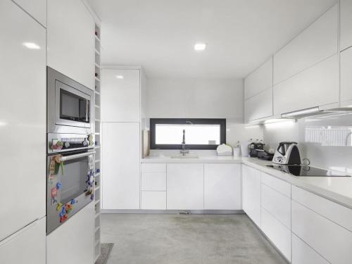 een witte keuken met witte kasten en een raam bij Jardins da Parede Villa in Parede