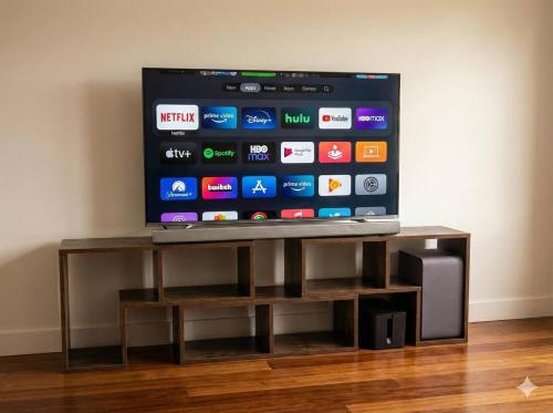a flat screen tv sitting on top of a wooden stand at Huge 3Bed House and Backyard & 4 Car Park spaces and Near Parramatta in Wentworthville