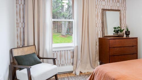 a bedroom with a chair and a dresser and a window at Charcoal Chalet by AvantStay A Design w Firepit in New Paltz