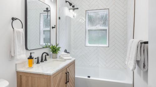 a bathroom with a sink and a tub and a mirror at Charcoal Chalet by AvantStay A Design w Firepit in New Paltz