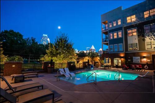a swimming pool with benches and a building at Queen City Getaway with Pool in Charlotte