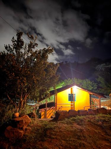 a yellow house with a light on it at night at Cabaña frente al Río-Curití-San Gil in Curití
