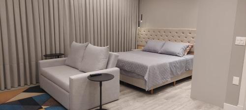 a bedroom with a bed and a couch and a chair at Flat Infinity 1504 Vista Mar in Itapema