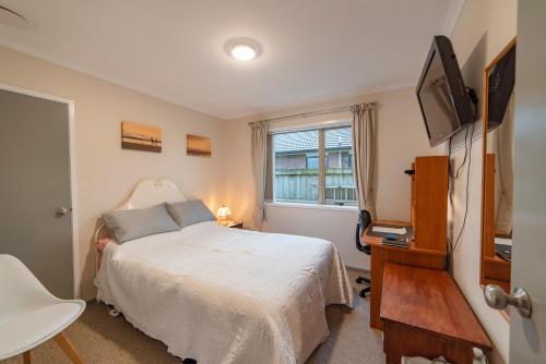 Relaxing home from home في إنفيركارجِِيل: غرفة نوم صغيرة بها سرير وتلفزيون