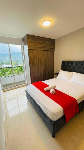 a bedroom with a large bed with a red blanket at Refugio de la cordillera in Armenia