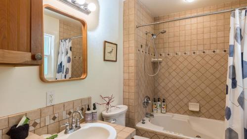 a bathroom with a sink and a tub and a toilet at Mid-Century Beach Cabin by AvantStay Walk to Beach in Coupeville