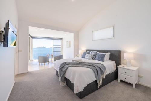a bedroom with a bed and a view of the ocean at Wanda Beach Waterfront , 161 Soldiers Point Rd - waterfront, air con, linen, Wi-Fi in Salamander Bay