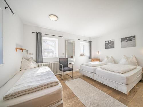 Un dormitorio con dos camas y una silla dentro. en Chalet Adriana, en Kirchberg in Tirol
