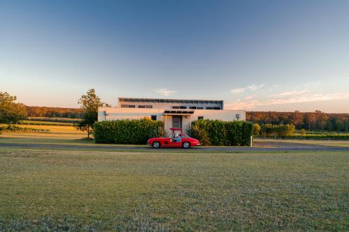 a red car parked in front of a building at Adina Vineyard in Lovedale