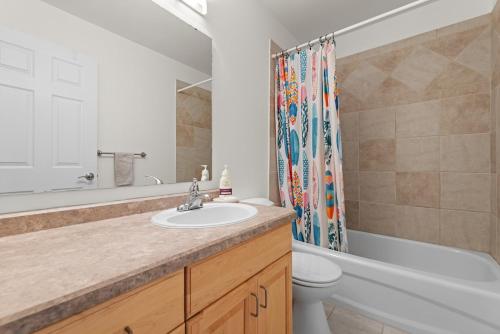 a bathroom with a sink and a toilet and a shower curtain at Stylish 3-Bedroom Home in Buena Vista in Saskatoon