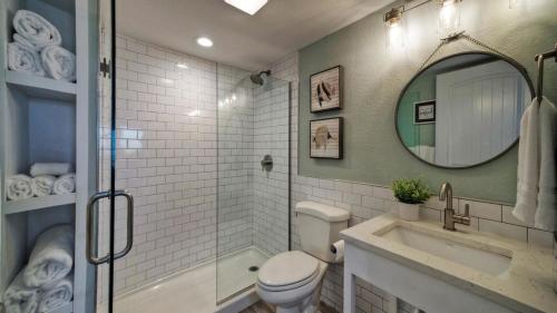 a bathroom with a toilet and a sink and a mirror at Beachfront Condo Prvt Balcony w View Pool Access Beach Happy by AvantStay in Port Aransas